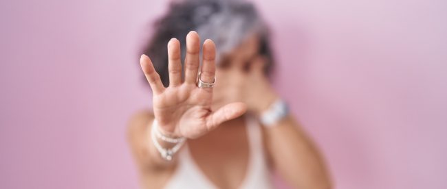 Middle age woman with grey hair standing over pink background covering eyes with hands and doing stop gesture with sad and fear expression. embarrassed and negative concept.