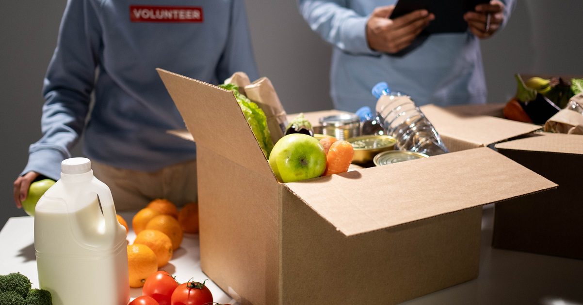 box of donated food with volunteer stood behind - article for Silver www.silvermagazine.co.uk