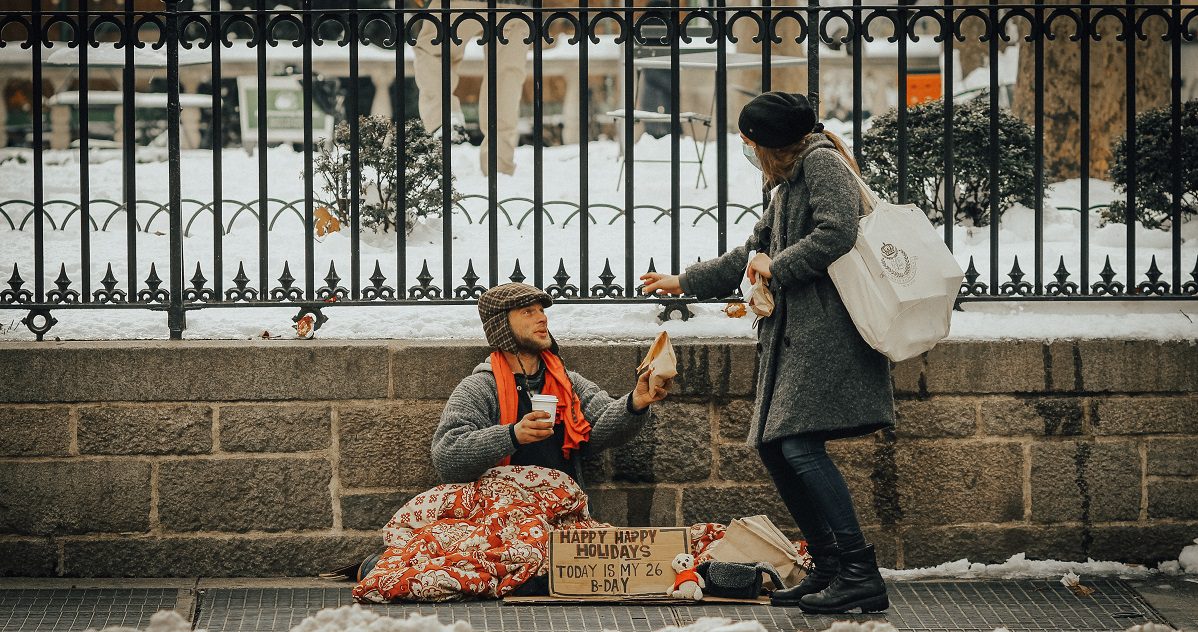 woman giving homeless man food and a hot drink - article on Silver www.silvermagazine.co.uk