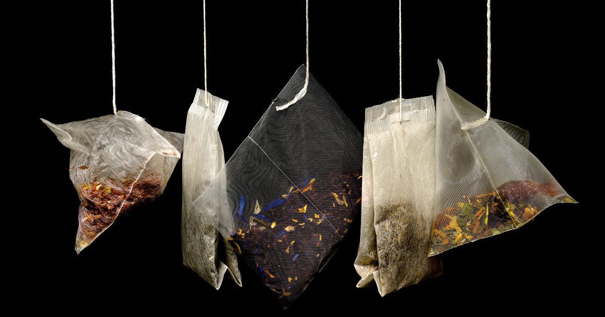 Different types of tea in tea bags hanging from string on black background for article about Brew Monday for Silver Magazine www.silvermagazine.co.uk