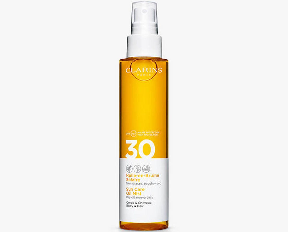 Tall amber bottle with white table and lid against a pale grey background. Clarins body and hair oil - summer beauty edit on Silver.