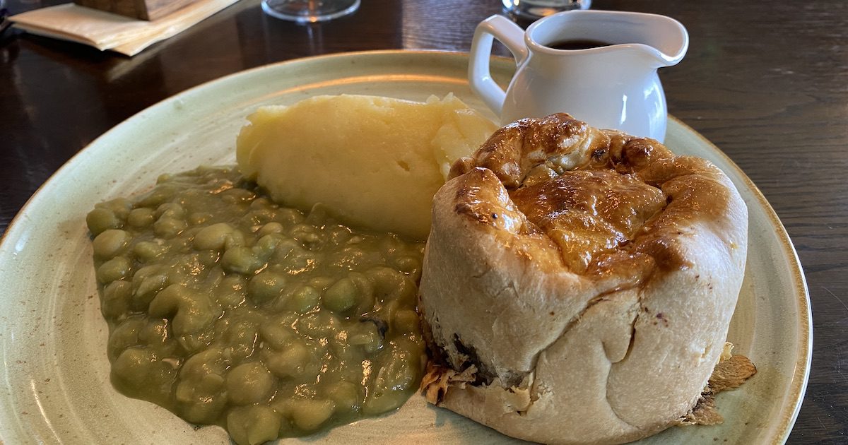 Image shows plate with generous pie, mashed potatoes, and mushy peas