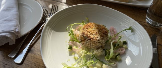 Plate of delicious food in the sun, showing fishcake and salad and pickles, part of the meal eaten at the spa for lunch