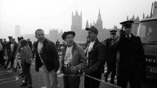 Black and white photo of Paul Burston and other members of ACT UP chained to Westminster Bridge