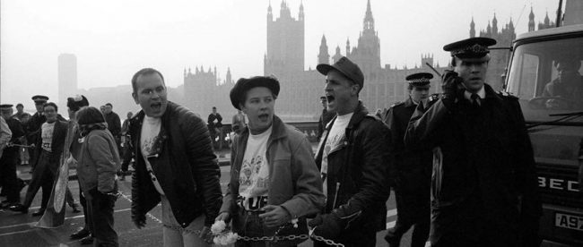 Black and white photo of Paul Burston and other members of ACT UP chained to Westminster Bridge