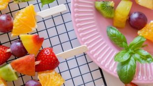 Colourful fruit skewers next to a pink plate. Healthy eating tips on Silver.