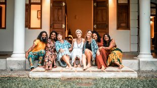 Seven visitors sat on the front steps of Kalukanda House huddled together smiling.