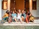 Seven visitors sat on the front steps of Kalukanda House huddled together smiling.