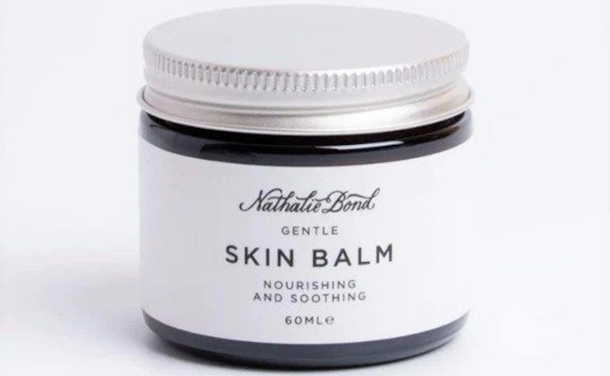Moisturising skin balm in a black glass tub with a silver lid. 