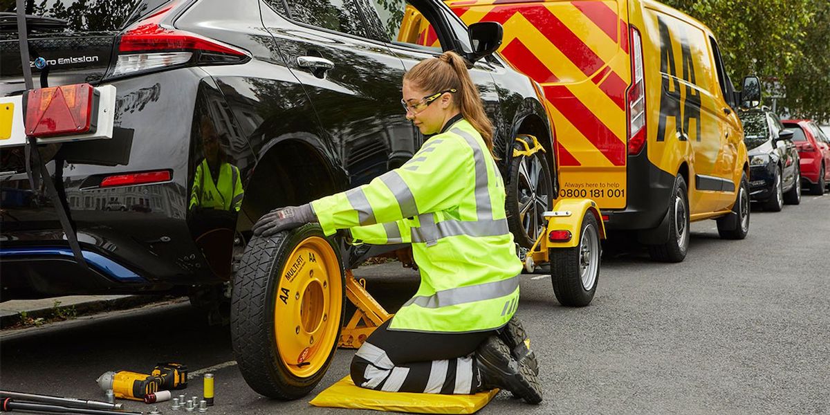 A women fixing the tyre of a car with an AA van in the background
