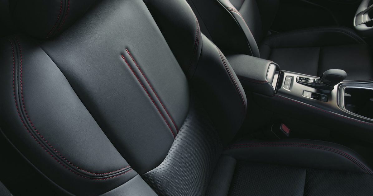 A black passenger car seat with red stitching.