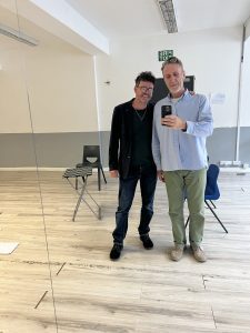 Mirror selfie of two men in a rehearsal studio. 
