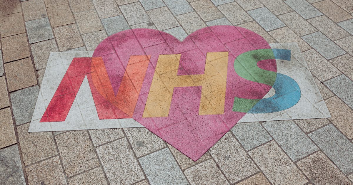 Red heart with NHS in rainbow colours - pavement art.