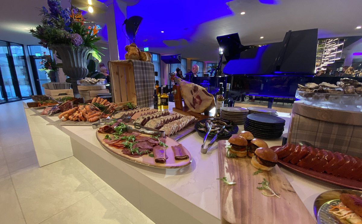 Image shows part of a buffet table laid up with meats, seafood, breads etc