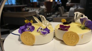 Image shows close up of two fancy mini lemon tarts with decorations on a plate