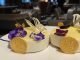 Image shows close up of two fancy mini lemon tarts with decorations on a plate