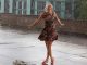 Image shows a woman dancing around on her own in the summer rain