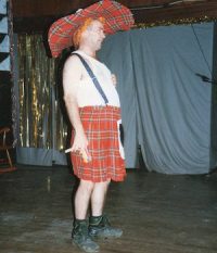 Ron Common dressed in red kilt and matching exaggerated oversized hat. Silver Magazine am dram theatre over 50 article