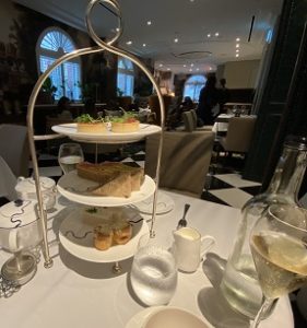 Image shows a tower of savoury afternoon tea selections like sandwiches and ham pastries