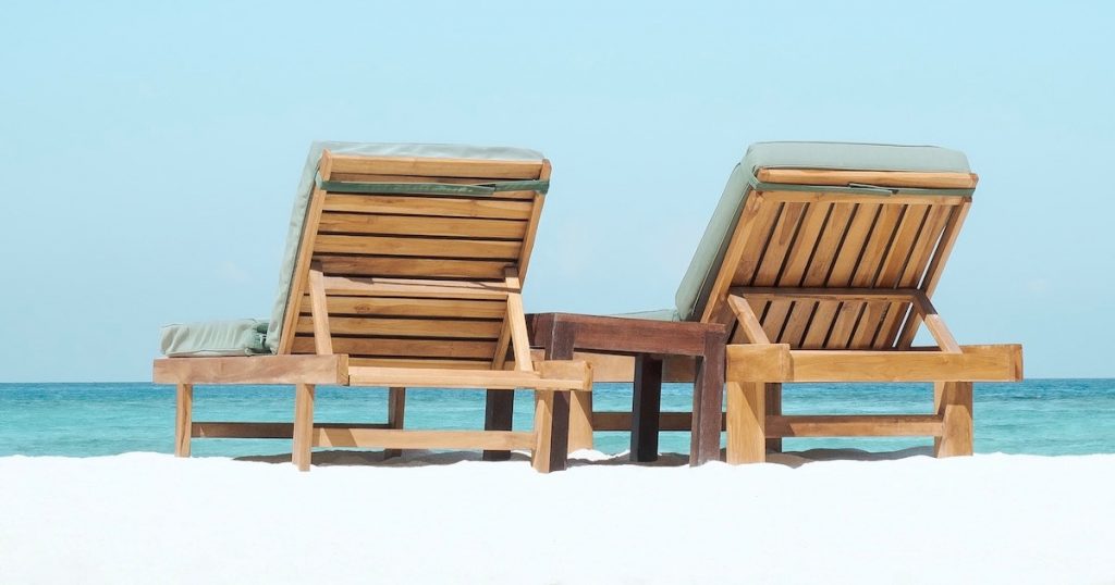 Blue sky, white sand beach and two wooden deck chairs