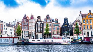 Colourful houses on the edge of canal in Amsterdam. September city breaks on Silver