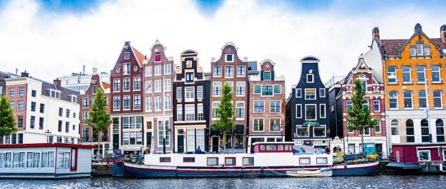 Colourful houses on the edge of canal in Amsterdam. September city breaks on Silver