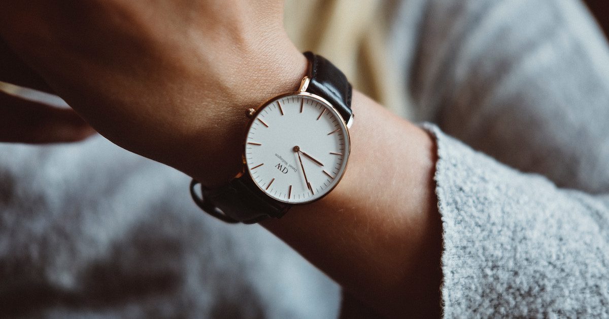 Leather watch with a white face on person's wrist. Wardrobe essentials autumn.