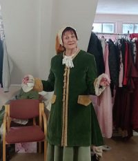 Elizabeth Gibson dressed in green pantomime costume. Doing theatre over 50