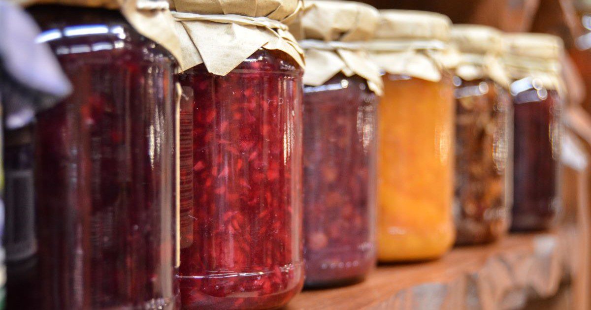 A row of assorted jam jars in reds, yellows and purples