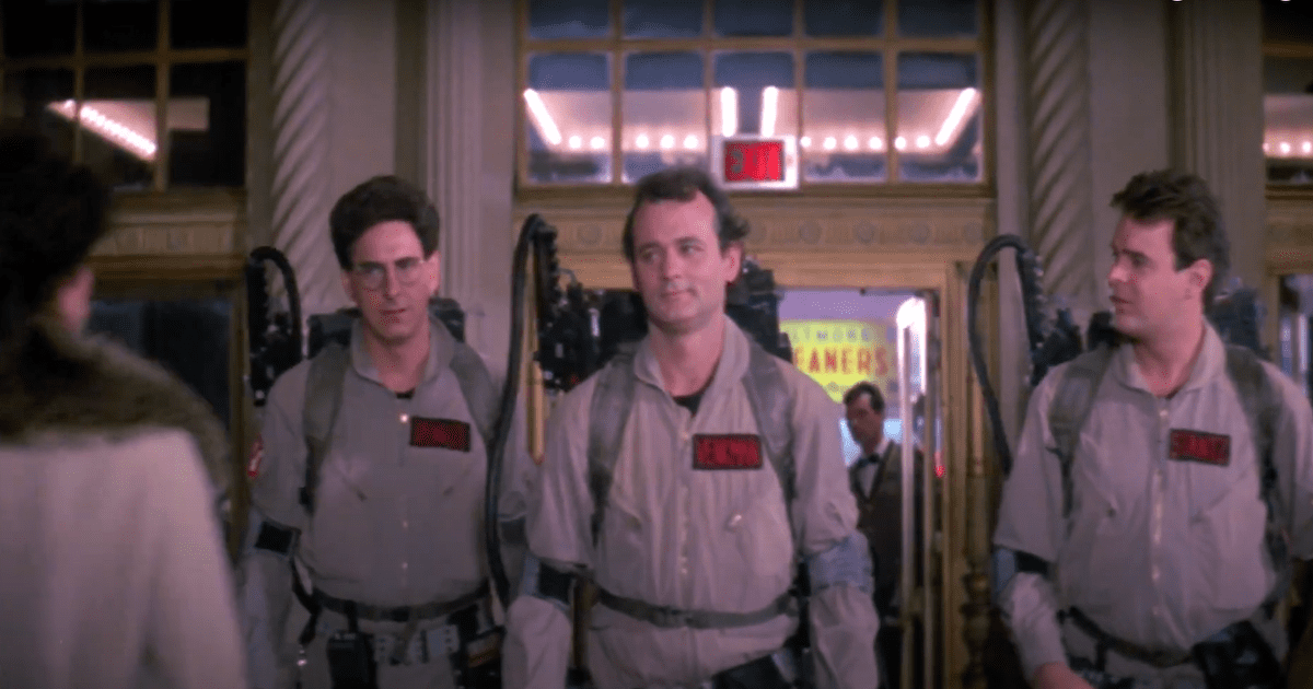 Three of the original ghostbusters stand in front of a building wearing their ghostbusters uniforms. Halloween films not scary