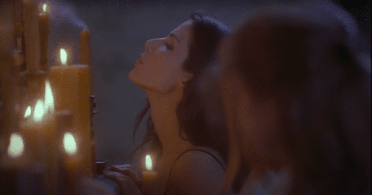 Witch sister in Practical Magic, played by Sandra Bullock, looking up in front of candles. Halloween films not scary 