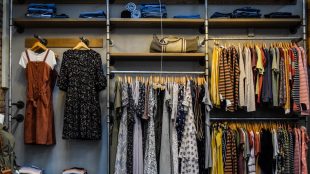 Image of clothes hanging on display and jeans folded on a shelf above. Capsule wardrobe over 50s advice on Silver