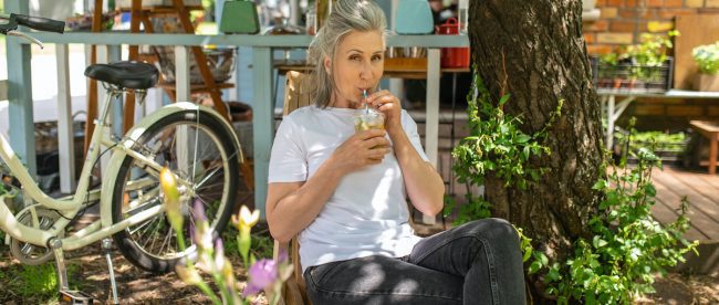 A mature woman sitting outside and drinking her cocktail