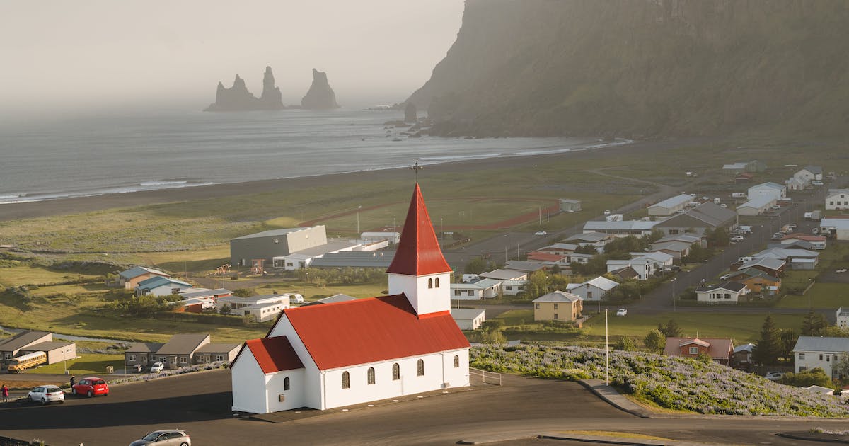 View across small Icelandic town with a terracotta roofed church style building sitting proudly at the front of the town.