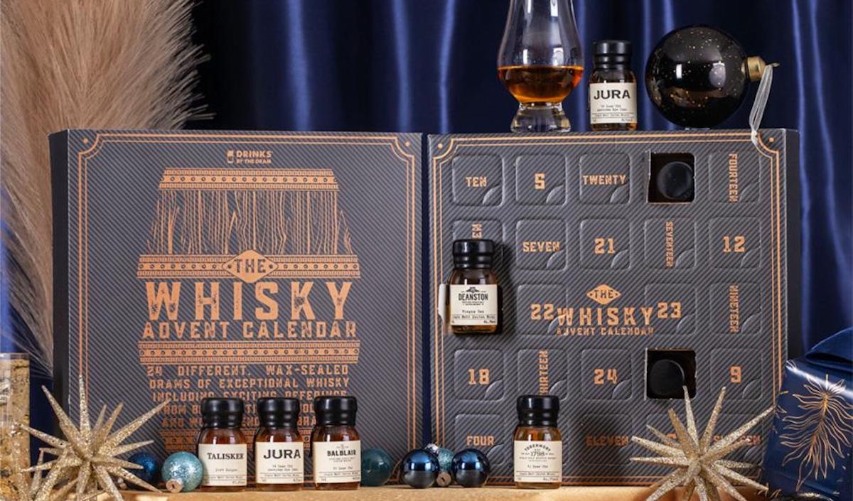 Whiskey advent calendar in dark grey with numbered doors. Small bottles of amber whiskey sat on top of the calendar and in front of it. Christmas advent calendar round up on Silver