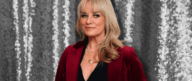 Tamzin Outhwaite stands in red velvet suit and black blouse against a glittery backdrop. Women's party wear