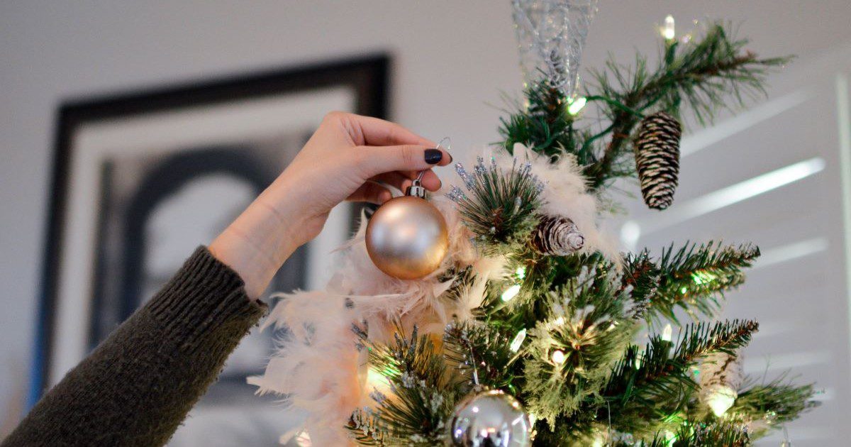 Image of a hand putting a bauble on a Christmas tree.