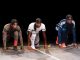 Three young black men dressed in sports gear are lined up as though ready to run a race, in a scene from the play